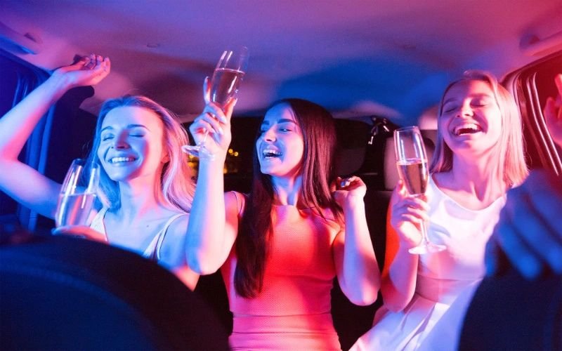 Three women enjoying a birthday celebration, holding champagne glasses in a lively, colorful ambiance.